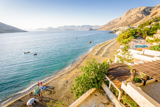 Beautiful sunny holiday view to the greek beach blue sea with crystal clear water beach with some boats fishing cruising surrounded by hills mountains, Kalymnos Island, Kos, Dodecanese, Greece 