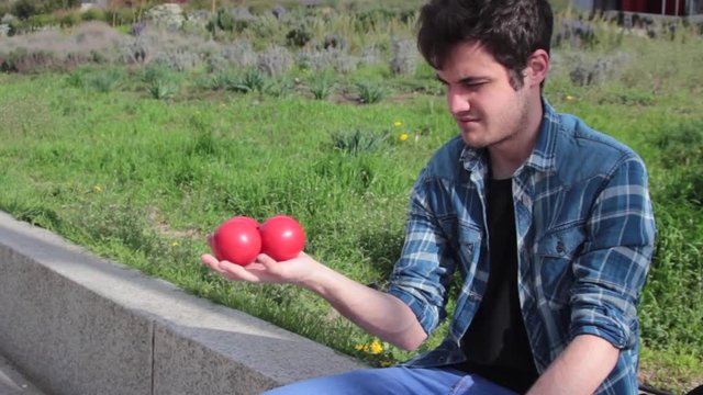 Joven haciendo malabares con pelotas rojas 