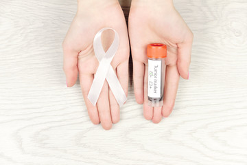 Oncological disease concept. Hands holding white ribbon as a symbol of lung cancer and negative...