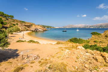 Fototapeta na wymiar Beautiful sunny coast view to the greek blue sea with crystal clear water beach with some boats fishing cruising surrounded by hills, Kokkina Beach, Leros, Dodecanese Islands/ Greece – July 18 2017