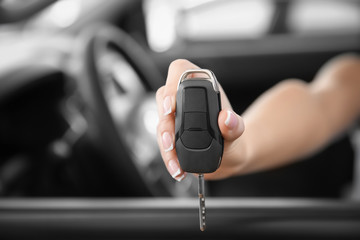 Young woman with key sitting in driver's seat of new car, closeup