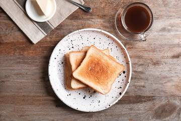 Plate with toasted bread and cup of coffee on wooden background, top view