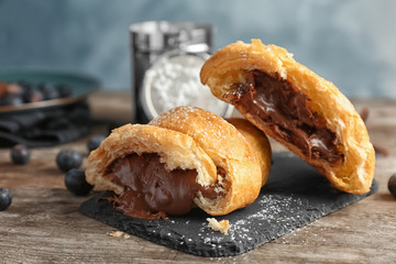 Tasty croissant with chocolate on wooden table