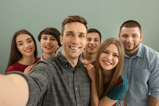 Happy friends taking selfie on color background