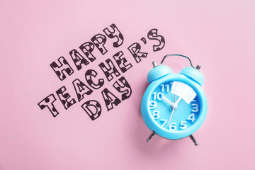 Alarm clock and text HAPPY TEACHER'S DAY on color paper