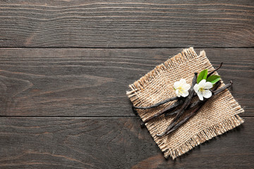 Vanilla sticks and flowers on wooden background