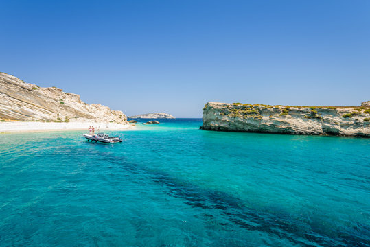 Beautiful sunny coast view to a small greek island and crystal clear blue water beach with some boats cruising and people swimming, White Island, Aspronisi, Leros, Dodecanese/ Greece &ndash; July 22 2017