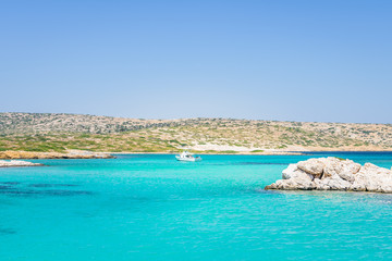 Beautiful sunny coast view to a small greek island bays and crystal clear blue water beach like paradise with some boats cruising or fishing, Arki, Tiganakia Beach, Leros, Dodecanese/ Greece 