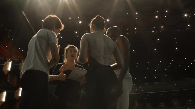 Young dancers and woman in group on stage with digital tablet having a discussion.