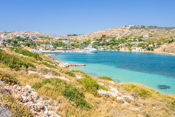 Beautiful sunny coast view to a small greek village harbor white houses with crystal clear blue water beach cruising fishing some boats and hills background, Arki Island, Leros, Dodecanese, Greece