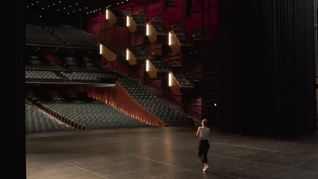 Young female dancer entering stage and rehearsing ballet dance.