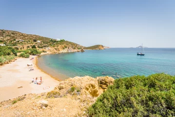 Foto op Plexiglas Peaceful sunny coast view to a empty greek holiday bay with crystal clear blue water sandy beach for sunbathing and some boats cruising fishing in background © Thomas Jastram