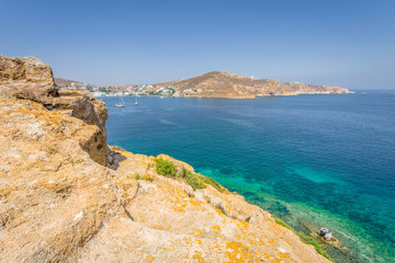 Fototapeta na wymiar Beautiful sunny holiday coast view to a empty holiday bay with crystal clear blue water sandy greek beach for sunbathing and some boats cruising fishing, Patmos Island, Kos, Dodecanese/ Greece