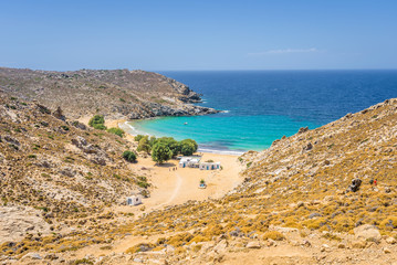 Fototapeta na wymiar Beautiful sunny coast view to the greek beach Psili Ammos and blue aegean sea with crystal clear water sandy beach with some boats fishing cruising small hills covering, Patmos, Dodecanese, Greece 