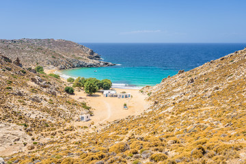 Fototapeta na wymiar Beautiful sunny coast view to the greek beach Psili Ammos and blue aegean sea with crystal clear water sandy beach with some boats fishing cruising small hills covering, Patmos, Dodecanese, Greece 