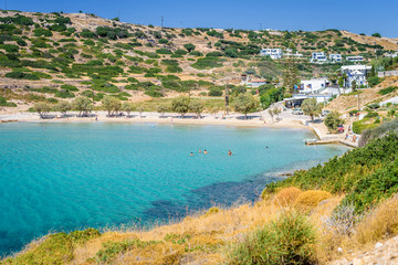 Fototapeta na wymiar Lipsi, Patmos Island, Dodecanese, Greece: Beautiful sunny coast view to a cozy holiday bay with crystal clear blue water sandy beach for sunbathing and some boats cruising fishing