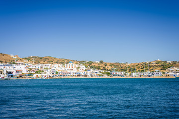 Fototapeta premium Lipsi, Patmos Island, Dodecanese, Greece: Beautiful sunny coast view to a cozy holiday bay with crystal clear blue water sandy beach for sunbathing and some boats cruising fishing