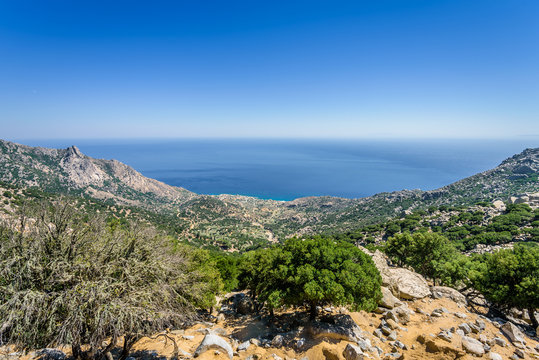 Beautiful sunny greek village town church and harbor view to the blue sea with crystal clear water and fishing boats cruising yacht at shore, Ikaria Island, Karkinagri, Sporades/ Greece &ndash; 08 01 2017