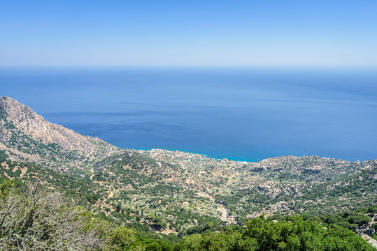 Beautiful sunny greek village town church and harbor view to the blue sea with crystal clear water and fishing boats cruising yacht at shore, Ikaria Island, Karkinagri, Sporades/ Greece &ndash; 08 01 2017