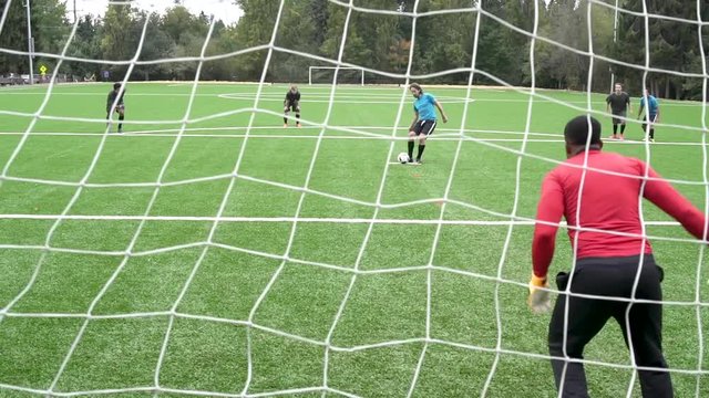 Male soccer player scoring goal.