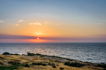 Beautiful colorful purple sunset sunrise coast view to a small greek town village with harbour fishing boats blue sea with crystal clear water, Ikaria Island, Armenisits, Sporades/ Greece - 08 05 2017