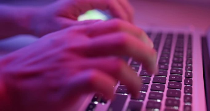 Working on keyboard with computer in red and blue light