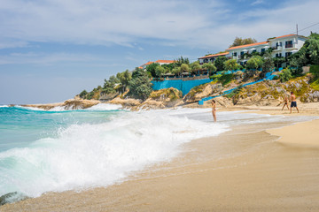 Beautiful sunny coast view to cozy holiday bay with crystal clear blue water sandy beach for sunbathing and heavy huge waves surfing from the greek sea, Ikaria Island, Armenistis, Greece - 08 04 2017