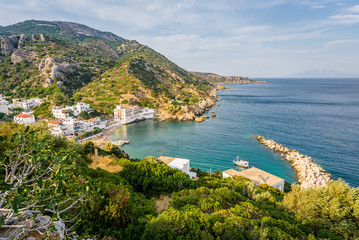 Fototapeta na wymiar Beautiful sunny summer coast view to the greek blue sea with crystal clear water relaxing holiday beach perfect for sunbath at the shore with a small rock, Agios Kirykos, Ikaria, Sporades, Greece 