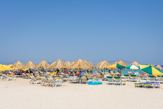 Beautiful sunny coast view to the greek beach mediterranean blue sea with crystal clear water and pure sandy beach while some tourists are sunbathing and relaxing in Marmari Tigaki