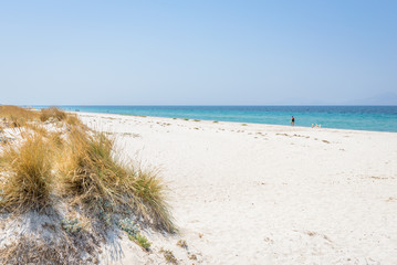 Beautiful sunny coast view to the greek beach mediterranean blue sea with crystal clear water and pure sandy beach while some tourists are sunbathing and relaxing in Marmari Tigaki
