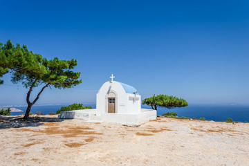 Holy white and blue greek orthodox chruch chapel of agios mamas the holy mother shining at an empty place over the greek sea hidden by the mountains on the island of Kos, Dodecanese, Greece