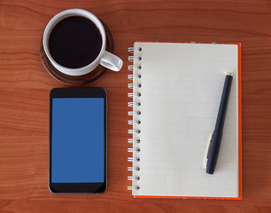 open notebook with blank pages, mobile phone and coffee cup.