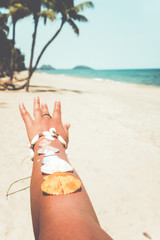 Fototapeta na wymiar Relaxation and Leisure in summer - Seashell on tanned girl arm at tropical beach in summer. vintage color tone