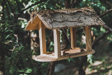 Wooden bird feeder on branch