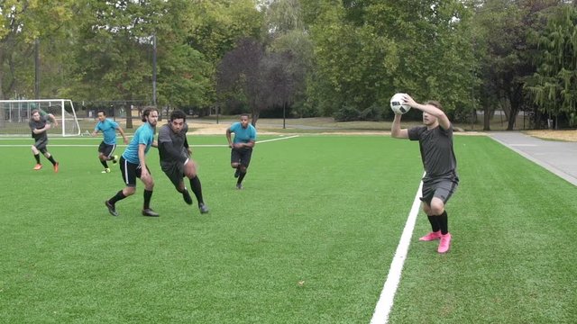 Male soccer player throwing ball onto pitch.