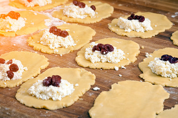 A close-up of the process of making buns from cottage cheese and berries on a wooden table