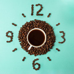 Coffee cup and roasted beans arranged as clock face on blue background, top view. Coffee time...
