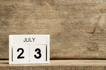 White block calendar present date 23 and month July on wood background