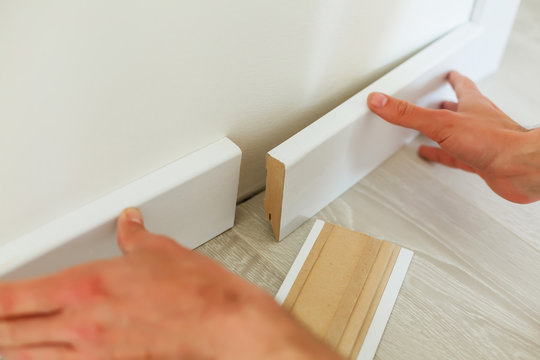 Mans Hands Putting White Baseboard, Do It Yourself