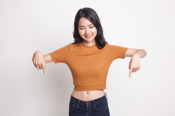 Beautiful young Asian woman point down to blank space.