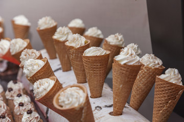 a lot of ice cream in waffle cones and cakes 