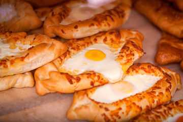 Close-up of fresh delicious freshly baked khachapuri buns with egg in straight rows