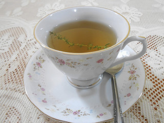 Hot Thyme Tea In Teacup On Saucer With a Teaspoon