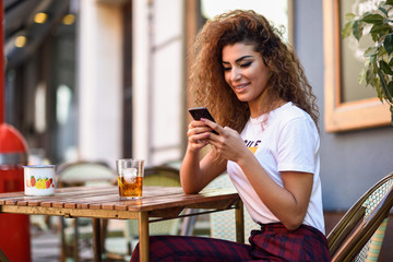 Arab woman in an urban bar at her smartphone.