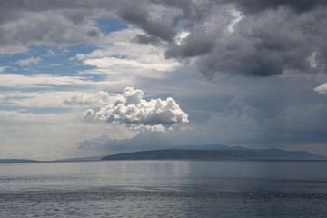 Seascape with beautiful clouds on croatian Adria and island silhouette on the horizon