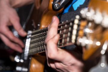 Hands and fingers of the guitarist's bass on the fretboard