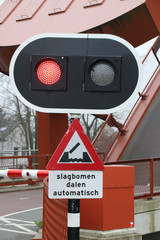 Red light at bridge for cyclist with tekst "slagbomen dalen automatisch" in dutch which means "barrier will go down automaticly"