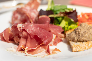 lorence, Tuscany/Italy - April 21, 2018. traditional Italian appetizers "antipasti": salami, dried meat (prosciutto), toast with tomatoes and olive oil (crostini), toast with pate, lettuce.