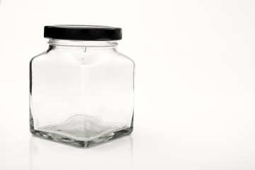 Square empty glass jar with black lid.