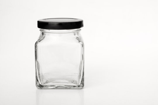 Square empty glass jar with black lid.